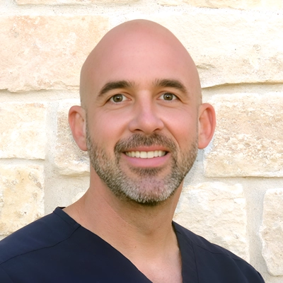 Matthew George smiling in front of a stone wall.